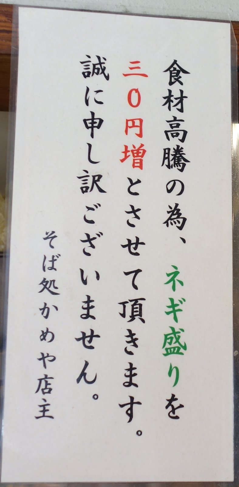 店内の貼紙「食材高騰の為、ネギ盛りを30円増とさせて頂きます。誠に申し訳ございません。そば処かめや店主」