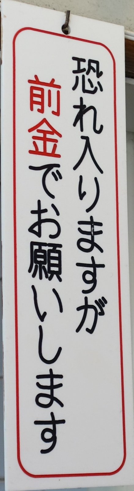 店内に貼られた「恐れ入りますが前金でお願いします」の案内札