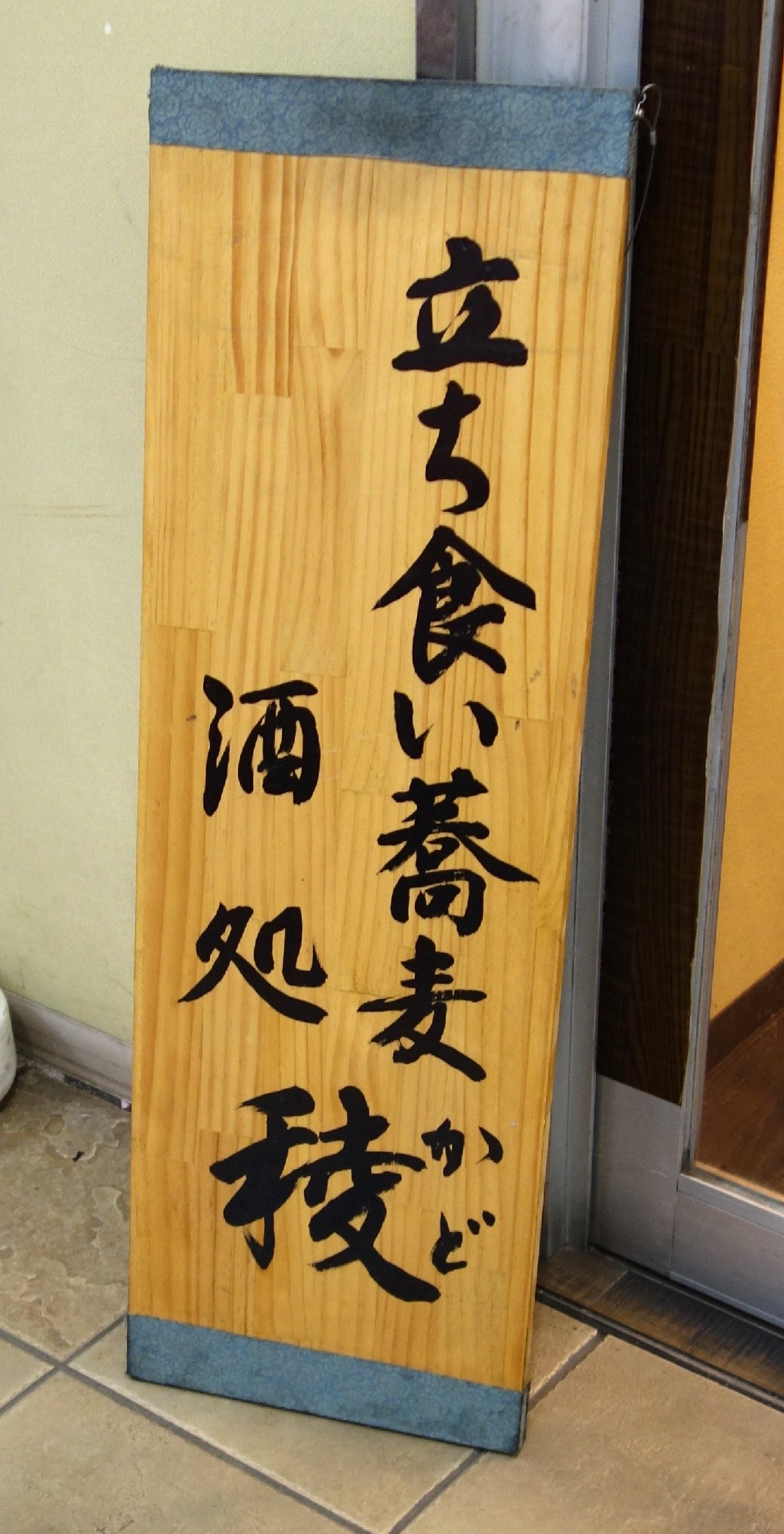 「立ち食い蕎麦 酒処 稜」と毛筆で書かれた縦書きの立看板