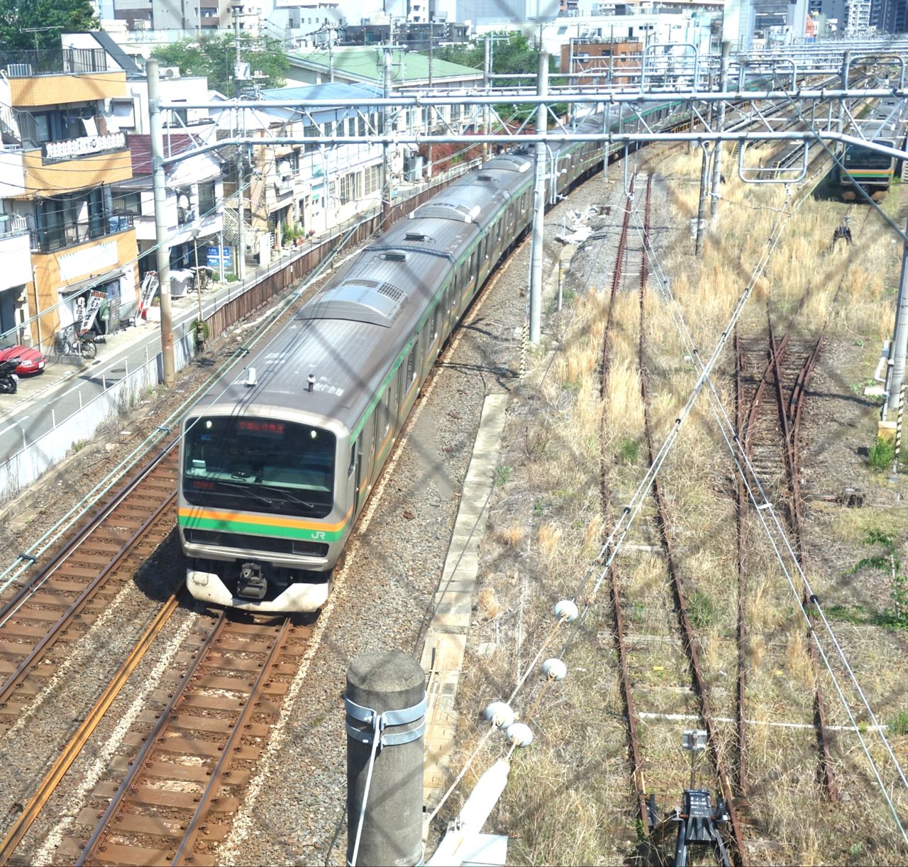 本線を走るオレンジと緑の帯の近郊電車を上から見たところ