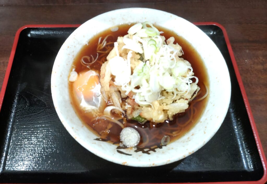 そばよし京橋店の天玉そばのかき揚げアップ。桜海老・長ネギ・玉ねぎと極細のそば