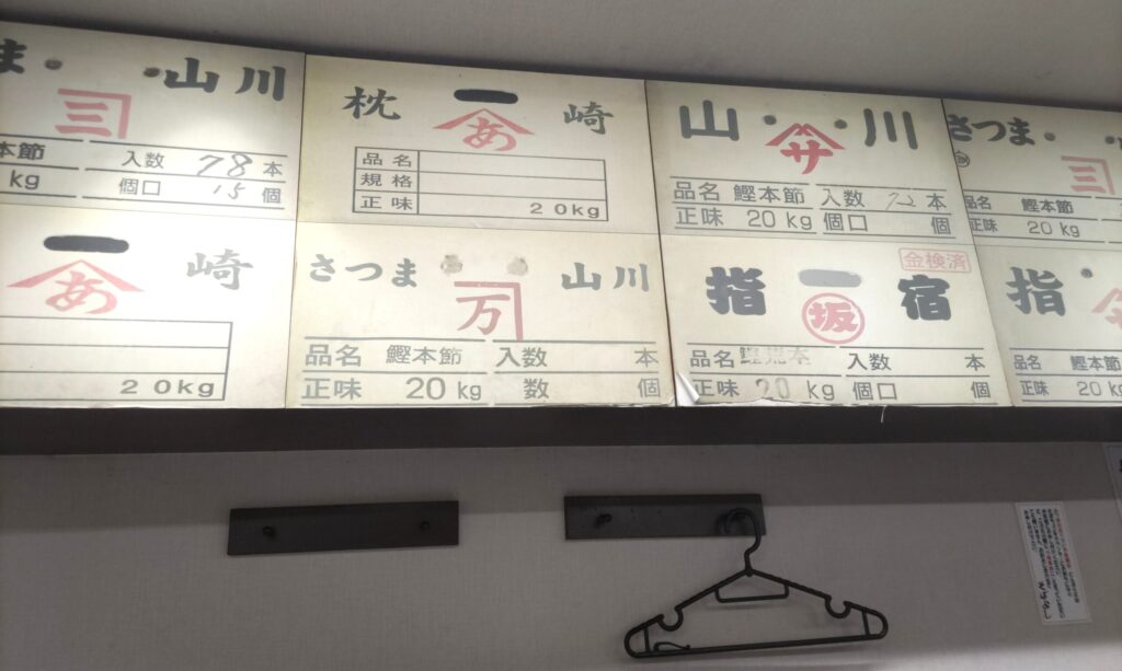 鰹節問屋直営を物語る、そばよし京橋店の店内に並ぶ鰹本節の問屋札（枕崎・山川・指宿など）
