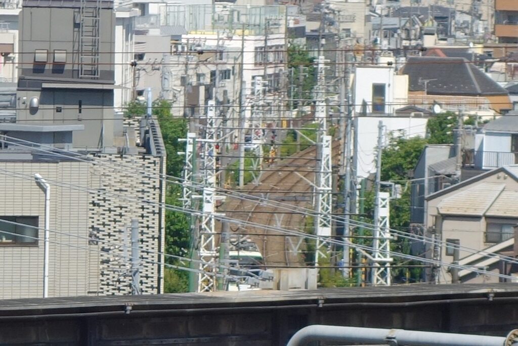 飛鳥山公園の展望広場から見た、街並みを抜けていく線路。遠くに都電荒川線（路面電車）の緑の車両が見える