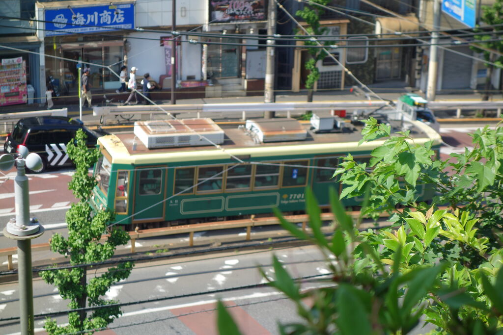 王子駅前の道路を走る、緑色のレトロ調デザインの都電荒川線7700形の車両