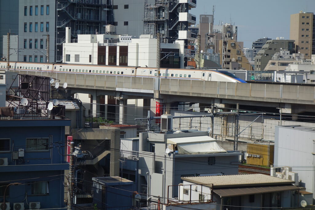 飛鳥山公園モノレール乗り場から見た、高架を走る白い車体のE7系新幹線