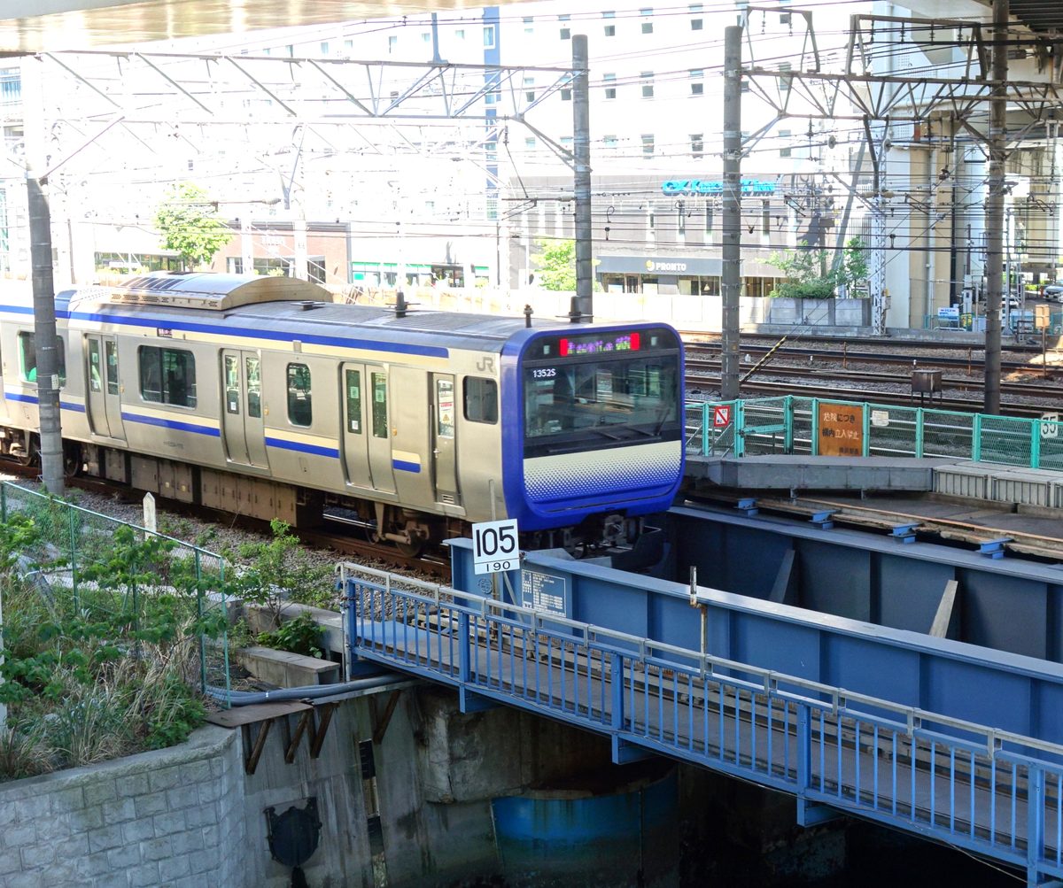 青い鉄橋を渡るJR横須賀線のE235系電車