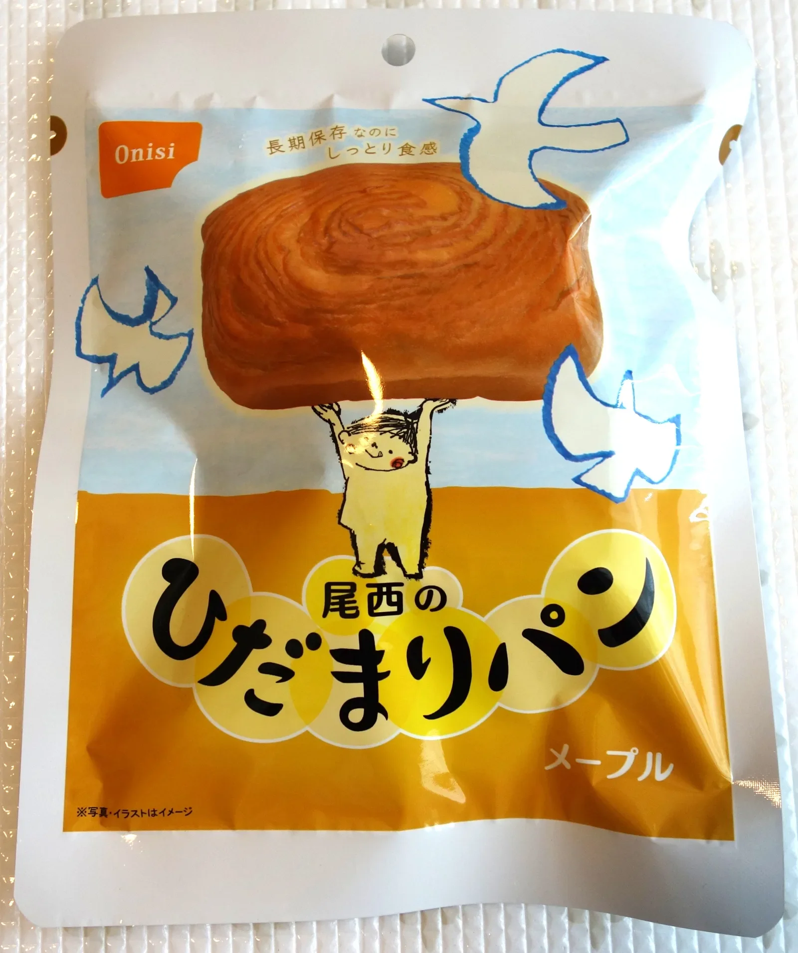 尾西のひだまりパン メープルのパッケージ表面。Onisiのロゴとハトのマーク、「長期保存なのにしっとり食感」の表示