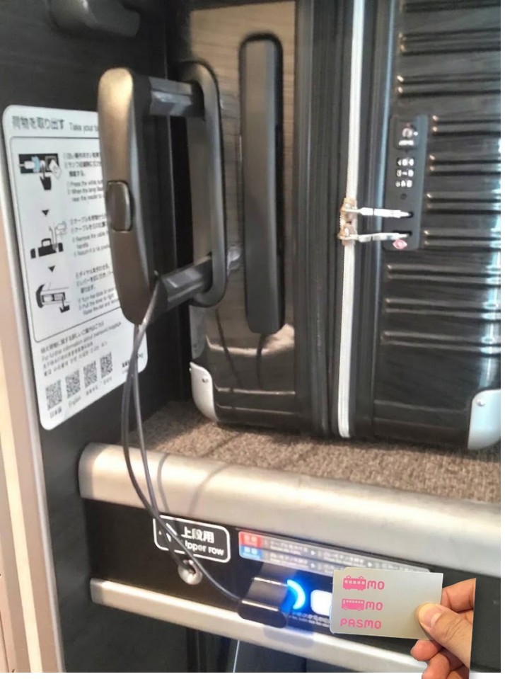 新幹線デッキ荷物置き場の上段。ケーブルを持ち手に通して差し込んだ状態で、パネル右側の「IC」読み取り部にPASMOをかざしている操作イメージ(現地写真と実物カードを合成)