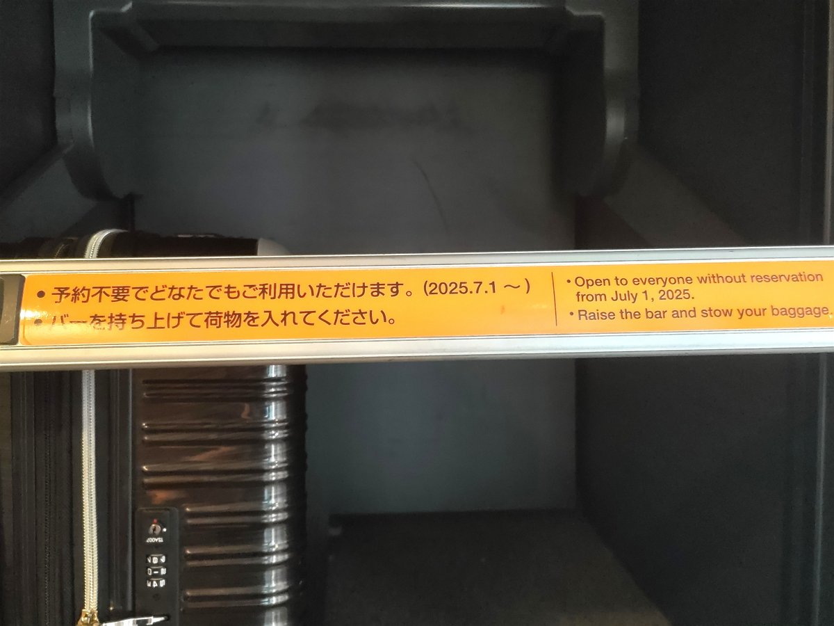 新幹線デッキ荷物置き場のバーに貼られた「予約不要でどなたでもご利用いただけます(2025.7.1〜)」の表示
