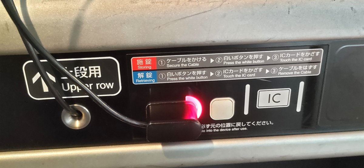 新幹線デッキ荷物置き場の上段用パネル。ランプが赤に変わり施錠完了