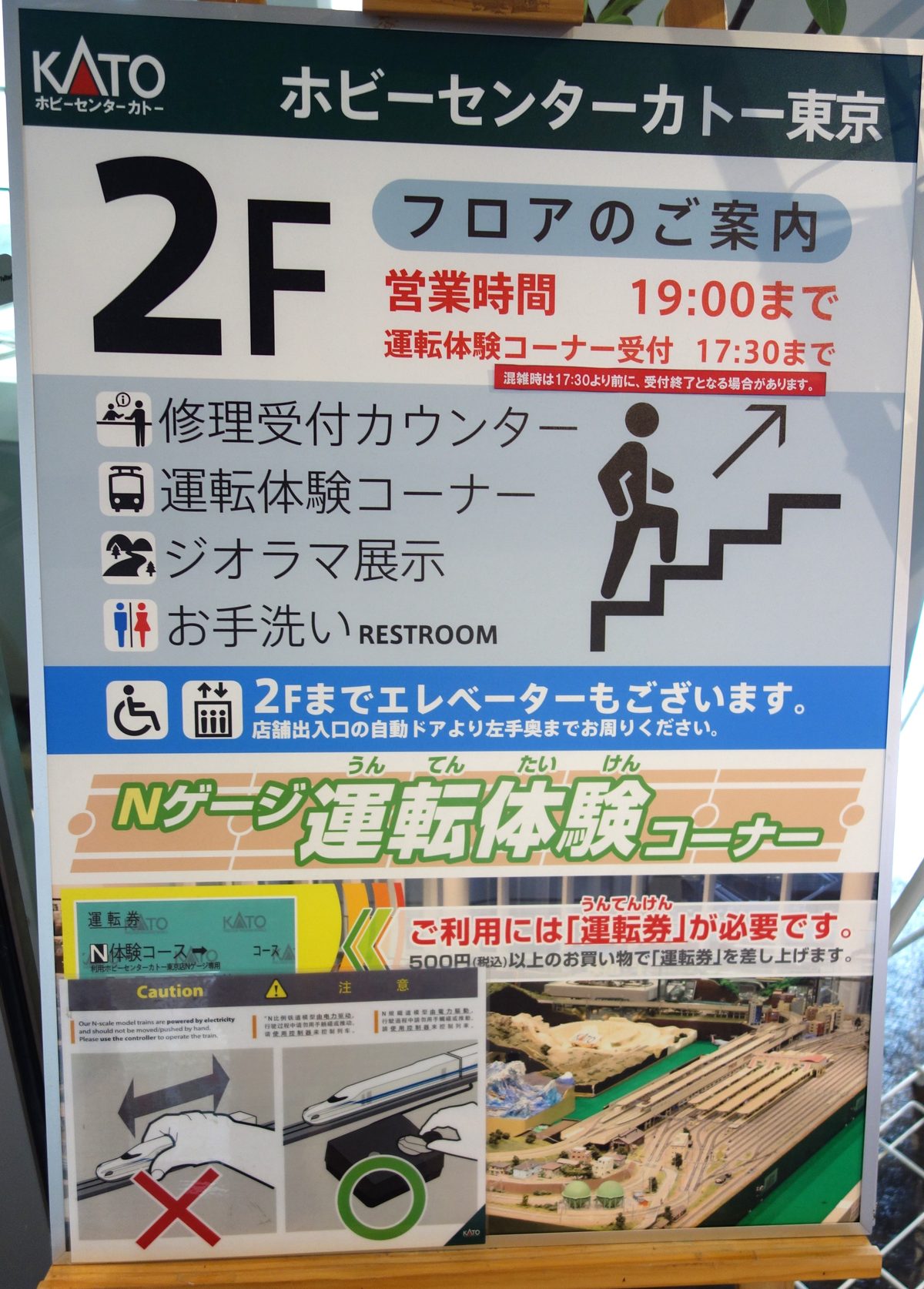 2階のフロア案内。修理受付カウンター・運転体験コーナー・ジオラマ展示・お手洗い
